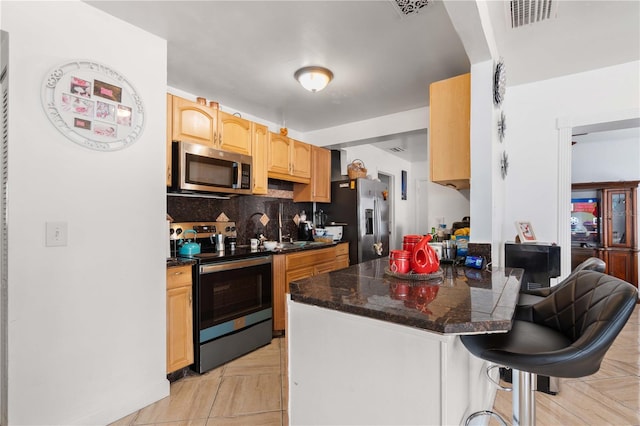 kitchen with a breakfast bar area, stainless steel appliances, visible vents, backsplash, and a peninsula