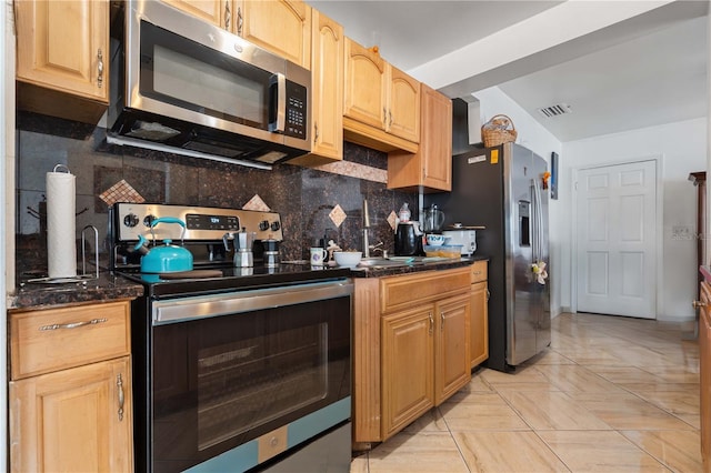 kitchen with appliances with stainless steel finishes, visible vents, a sink, and backsplash