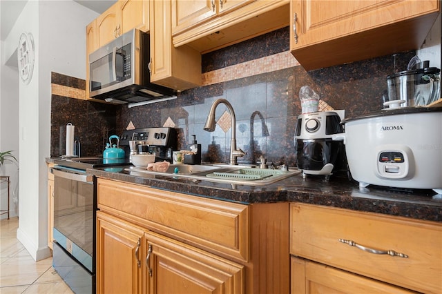 kitchen with a sink, appliances with stainless steel finishes, light tile patterned flooring, and backsplash