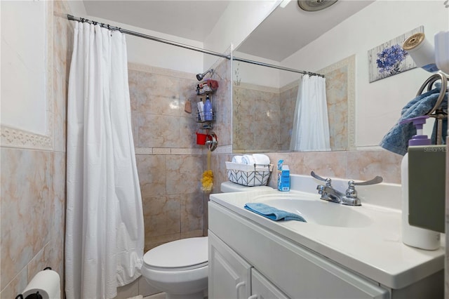 bathroom with toilet, a tile shower, tile walls, and vanity