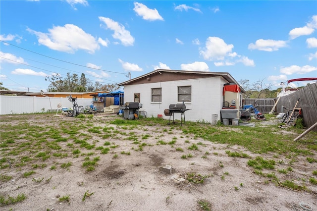 rear view of property with concrete block siding and a fenced backyard