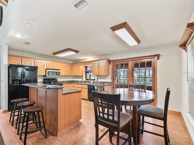 kitchen featuring light wood-style floors, a center island, visible vents, and black appliances