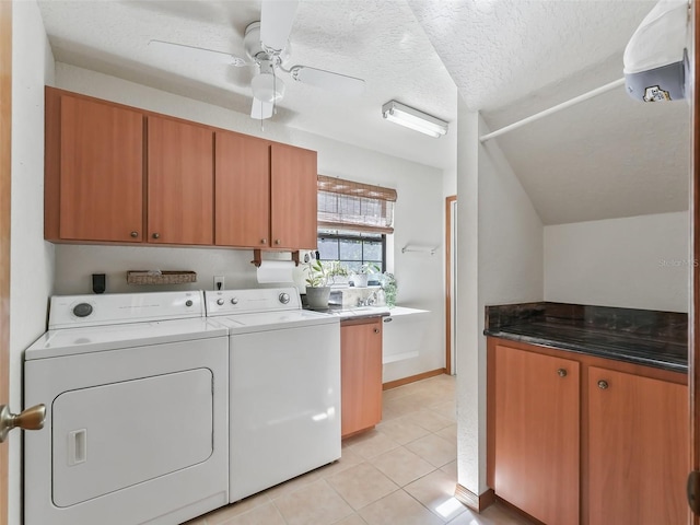 washroom with a textured ceiling, light tile patterned flooring, a ceiling fan, cabinet space, and washer and clothes dryer