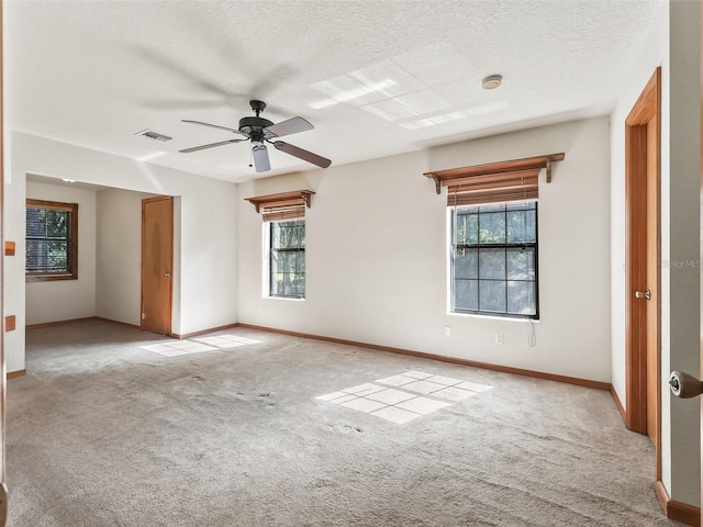 unfurnished room featuring a textured ceiling, carpet, visible vents, and baseboards