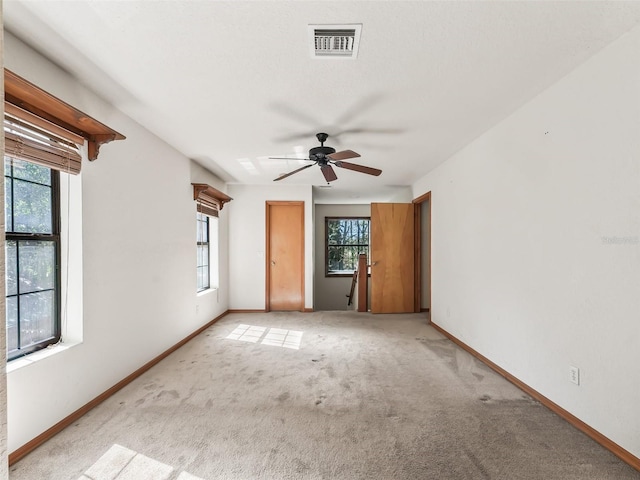 empty room with visible vents, ceiling fan, light carpet, and baseboards