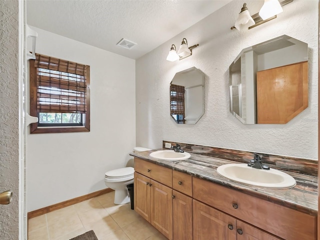 full bath featuring toilet, a textured ceiling, a sink, and tile patterned floors