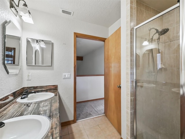 full bath with a textured ceiling, a stall shower, a sink, and visible vents