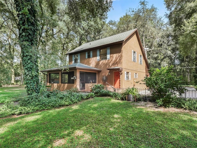 view of front facade featuring a sunroom, fence, stucco siding, and a front yard