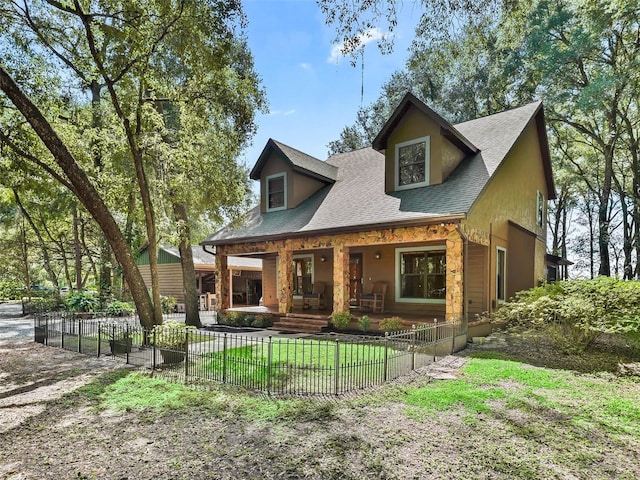 view of front of house with covered porch, a fenced front yard, a shingled roof, and a front yard