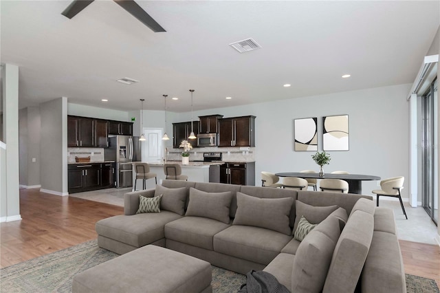 living room with visible vents, baseboards, light wood-type flooring, recessed lighting, and a ceiling fan