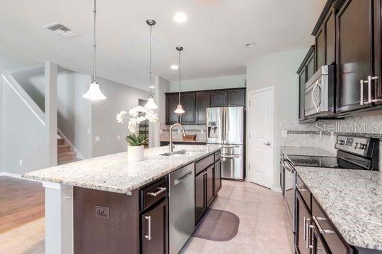 kitchen with visible vents, dark brown cabinets, stainless steel appliances, and a sink