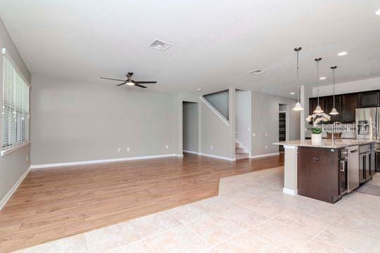 kitchen with decorative light fixtures, open floor plan, dark brown cabinets, and a ceiling fan