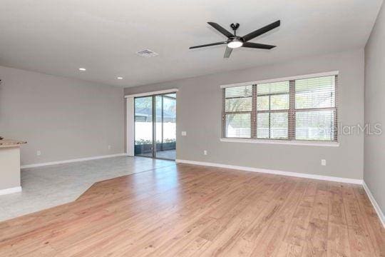 unfurnished living room with light wood finished floors, visible vents, baseboards, and a ceiling fan