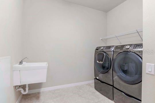 laundry area with a sink, baseboards, washing machine and dryer, and laundry area