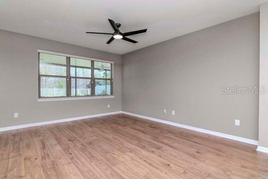 spare room with light wood-type flooring, baseboards, and ceiling fan