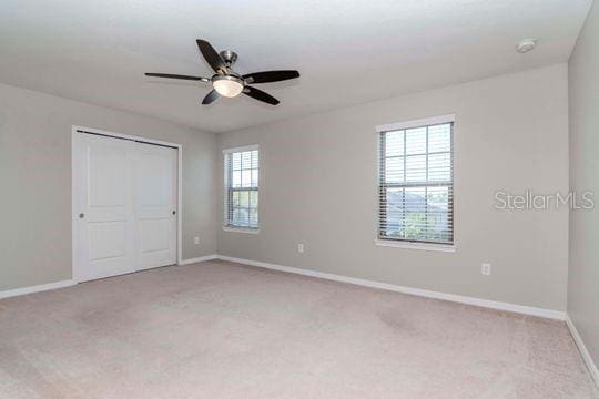 unfurnished room featuring baseboards, light colored carpet, and ceiling fan