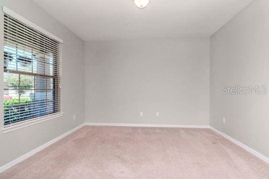 empty room with baseboards and light colored carpet