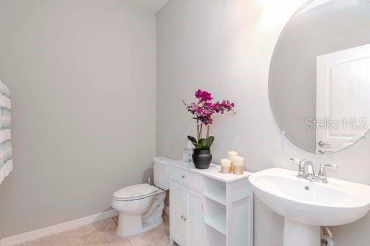 bathroom with tile patterned flooring, toilet, baseboards, and a sink