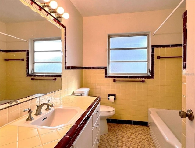 bathroom featuring tile walls, a wainscoted wall, vanity, and toilet