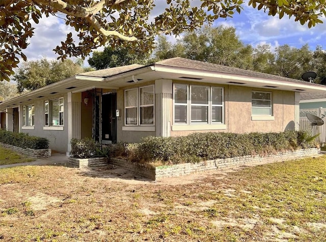 view of front facade featuring roof with shingles and stucco siding