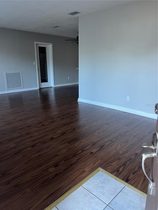 unfurnished room with visible vents, dark wood finished floors, baseboards, and ceiling fan