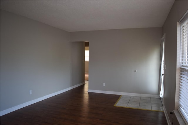 unfurnished room featuring a textured ceiling, baseboards, and wood finished floors