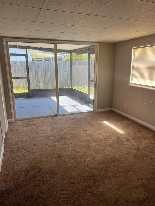 unfurnished room featuring a paneled ceiling, carpet, and baseboards