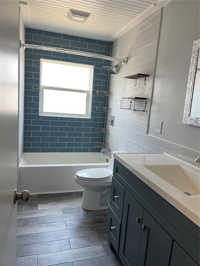 full bath with wood finish floors, visible vents, toilet, washtub / shower combination, and vanity