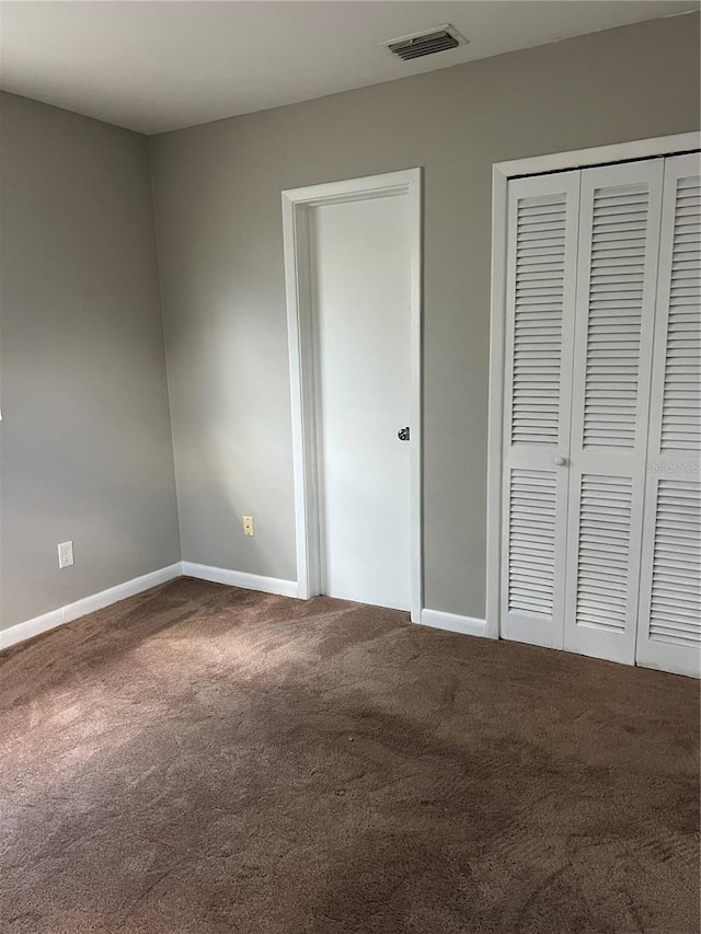 unfurnished bedroom with baseboards, carpet, visible vents, and a closet