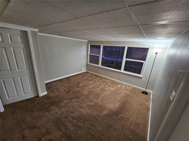 unfurnished bedroom featuring a paneled ceiling, baseboards, and carpet flooring
