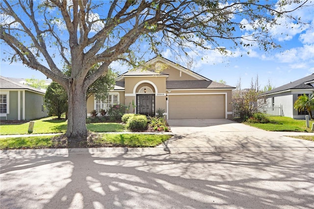 view of front facade with stucco siding, driveway, a front lawn, and a garage