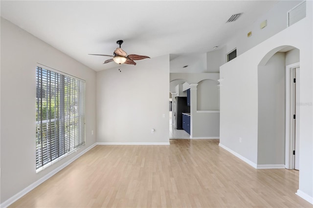 unfurnished living room with arched walkways, visible vents, light wood-type flooring, and ceiling fan