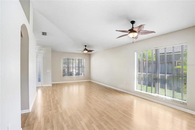 empty room with a ceiling fan, light wood-style floors, visible vents, and a wealth of natural light