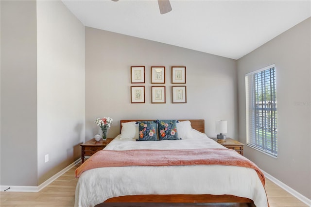 bedroom with ceiling fan, baseboards, light wood-style floors, and lofted ceiling