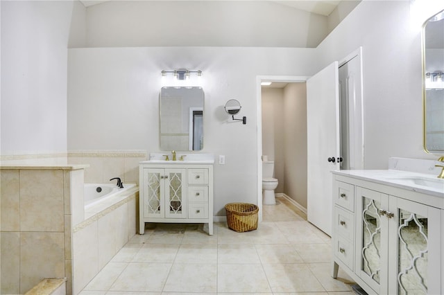 bathroom with toilet, a garden tub, two vanities, tile patterned floors, and a sink