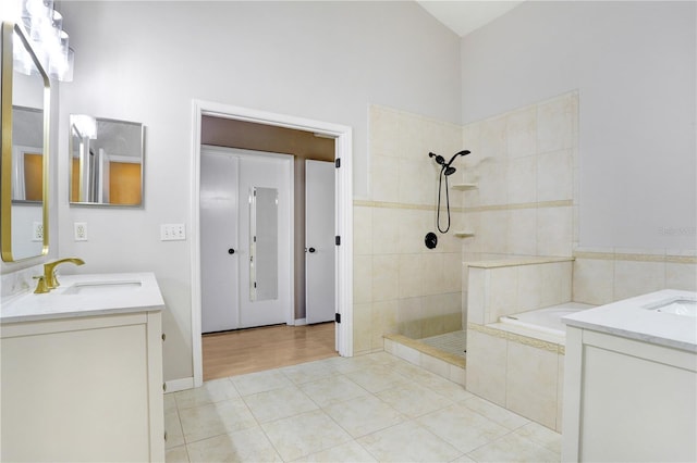 bathroom featuring a tile shower, tile patterned floors, two vanities, and a sink