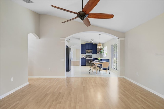 interior space featuring light wood-type flooring, baseboards, arched walkways, and vaulted ceiling