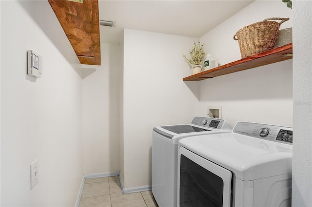 washroom featuring visible vents, baseboards, washing machine and dryer, light tile patterned floors, and laundry area