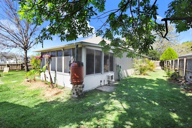 view of side of property with a yard, a fenced backyard, a wall mounted AC, and a sunroom