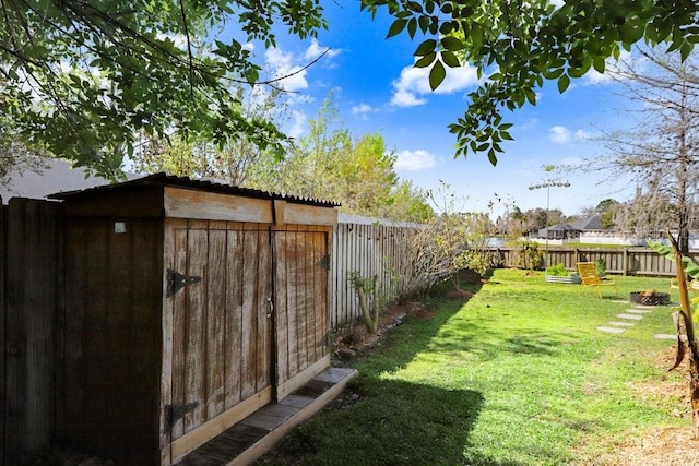 view of yard with an outbuilding, a fenced backyard, and a storage shed