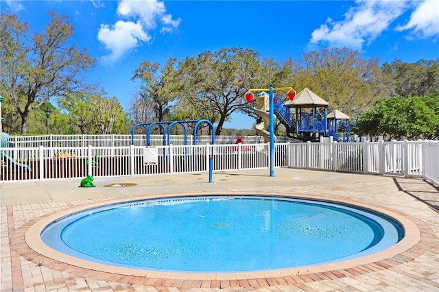 view of swimming pool with a patio area, a pool, fence, and playground community