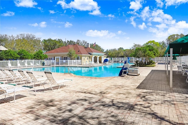 community pool with a patio and fence