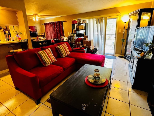 living room featuring ceiling fan, baseboards, a textured ceiling, and light tile patterned flooring