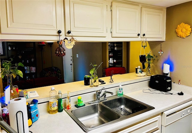 kitchen featuring dishwasher, light countertops, a sink, and white cabinetry