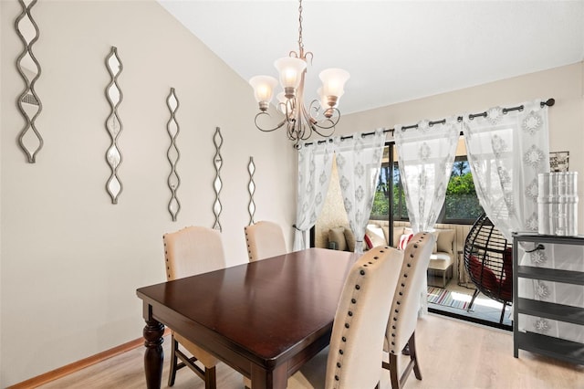 dining room featuring light wood-type flooring, a notable chandelier, and baseboards