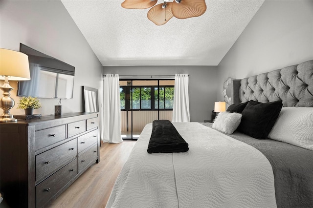 bedroom with light wood-style flooring, vaulted ceiling, and a textured ceiling