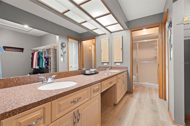 bathroom featuring toilet, a stall shower, a sink, and wood finished floors