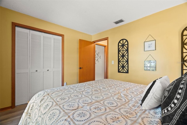 bedroom featuring a closet, visible vents, and wood finished floors