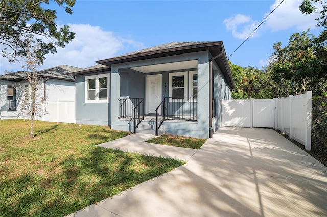 view of front of property featuring a front lawn, fence, covered porch, stucco siding, and a gate