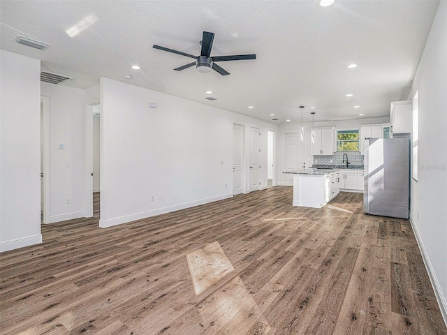 unfurnished living room with recessed lighting, wood finished floors, visible vents, and a sink